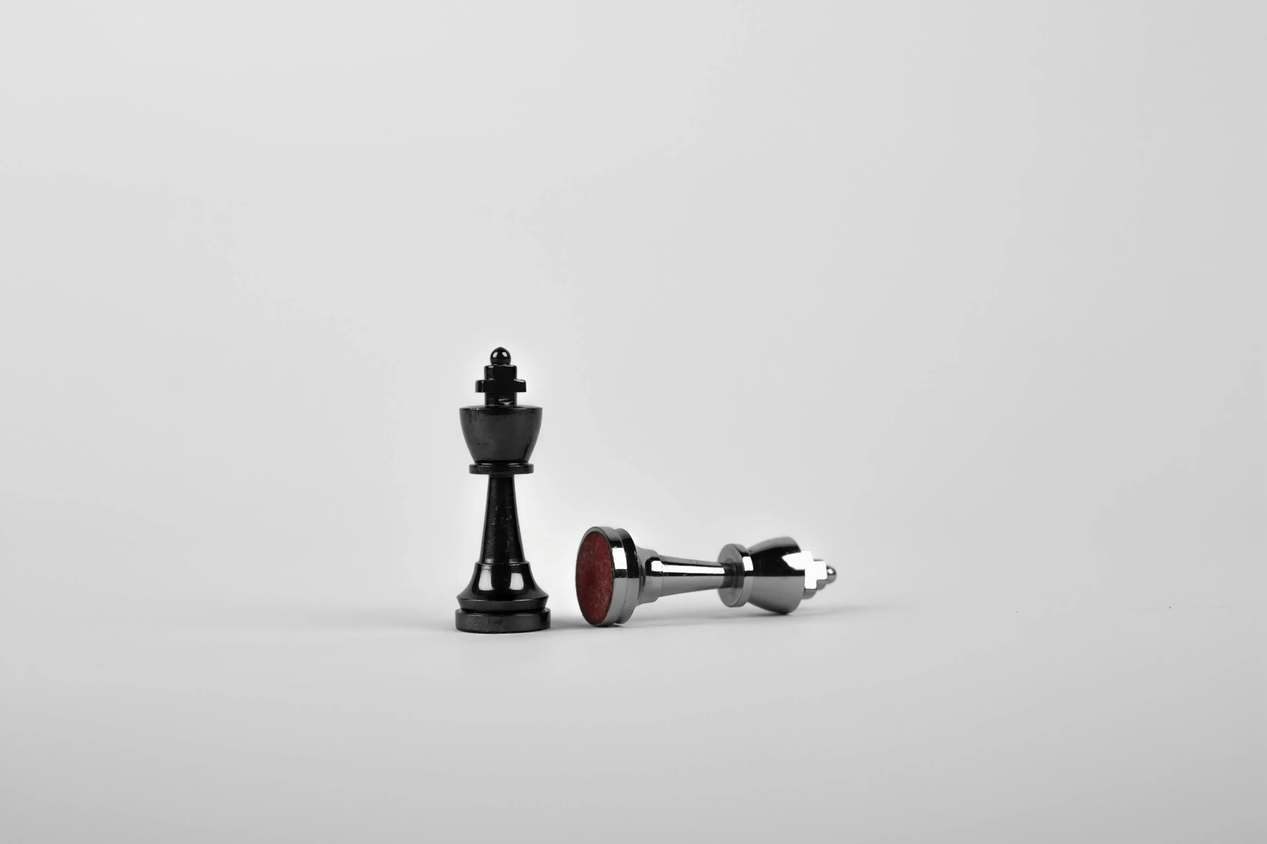 Black chess king standing beside a fallen silver king, symbolizing strategic execution by ORIGIN SWISS